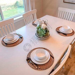 方形作物餐桌与餐具中心和椅子靠在棕色木地板上餐厅透过玻璃窗可以看到阳图片