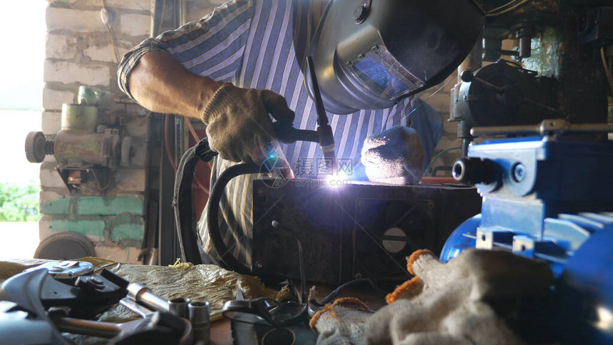 修理工焊接汽车的一些细节使用焊接机和其他专业设备在车库或车间工作的机械师焊工使用闪光防护面罩图片