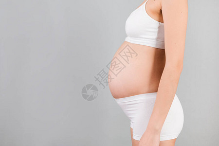 蓝色背景下孕妇腹部的特写女孩穿着白色内衣生育概图片