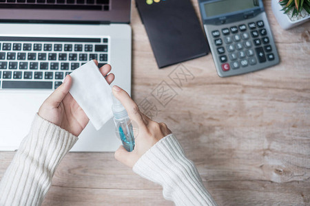 女在家办公和在线学习期间用湿巾纸和酒精消毒剂在工作场所清洁笔记本电脑图片