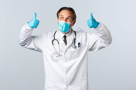 戴着医用口罩和手套的快乐的医生竖起大拇指图片