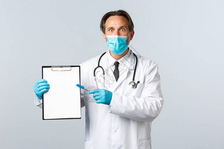 戴着医用口罩和手套的男医生震惊地指着剪贴板图片