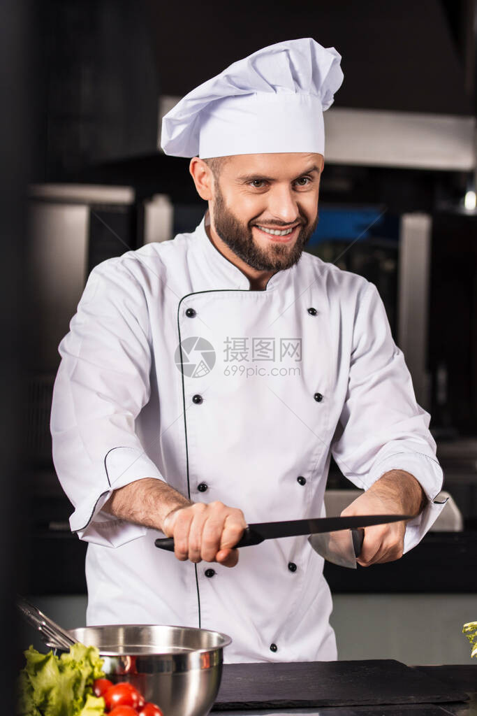 餐厅厨房的厨师人职业男拿着交叉刀在厨房摆姿势白色制服的微图片
