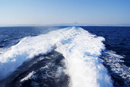 蓝色海中的一艘船引发了波浪的泡沫痕迹图片