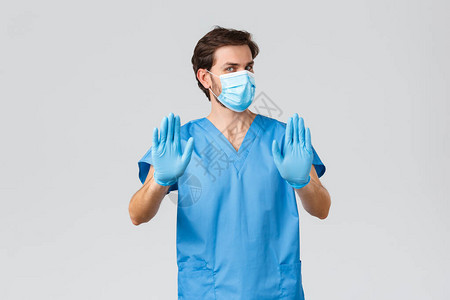 戴着医用口罩手套和磨砂膏的不情愿和不高兴的医生图片