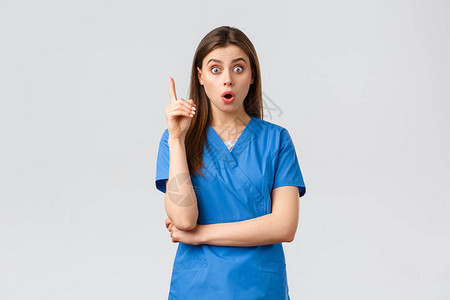 兴奋的女护士或穿蓝色衣服的医生举起一根手指图片