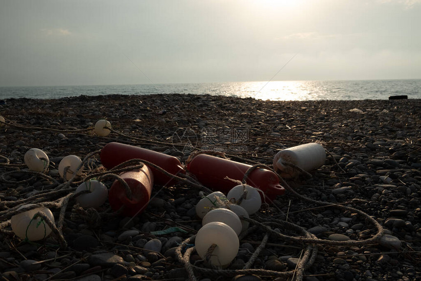 用电缆从海边的渔网中浮出水面拖网的配件位于鹅卵石上黑海的岸线晚图片