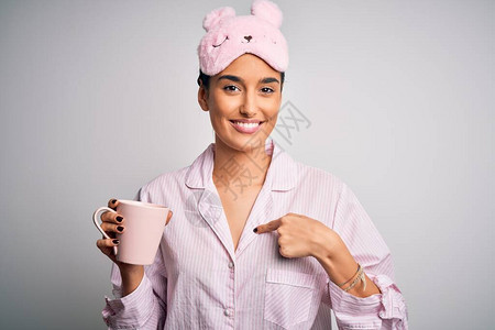 穿着睡衣和睡眠面罩的褐发美女喝着咖啡图片