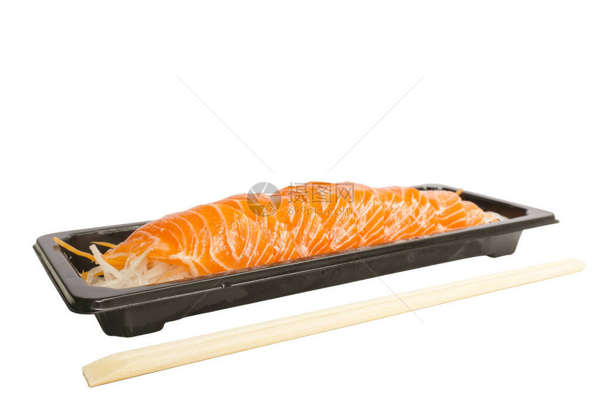 一排三文鱼生片放在小黑盘的蔬菜片上图片