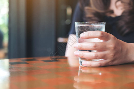 女士手握着冷水杯放在桌图片