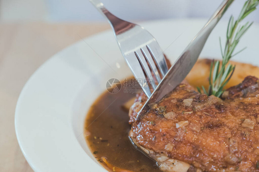 使用刀和叉子在木桌上吃炖鸡肉图片