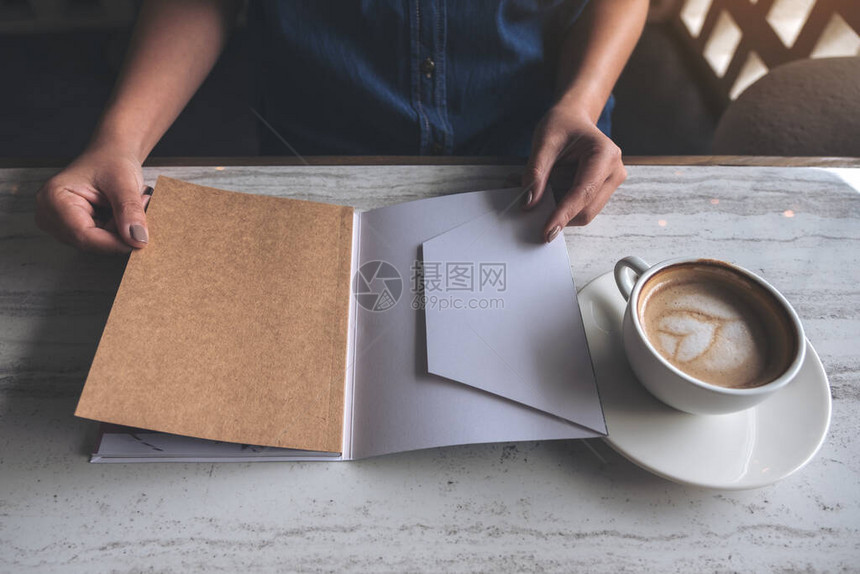 一位女在现代咖啡馆开书时用咖啡杯放在桌图片