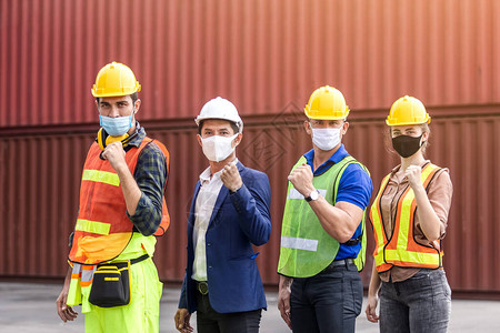 团队工程技师和工头及在货集装箱运输区佩戴防护面罩和安全黄色头盔的伴侣图片