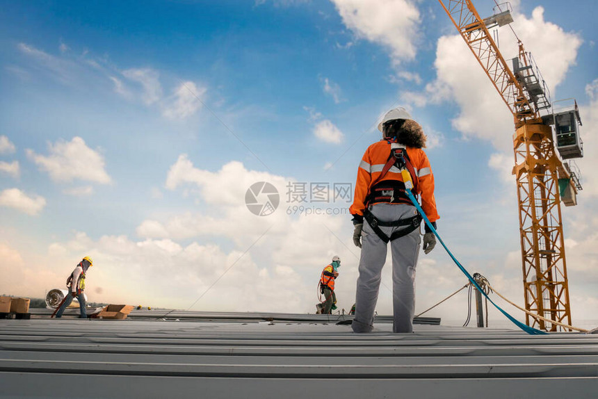 穿着安全带和安全线的建筑工人在金属工业屋图片