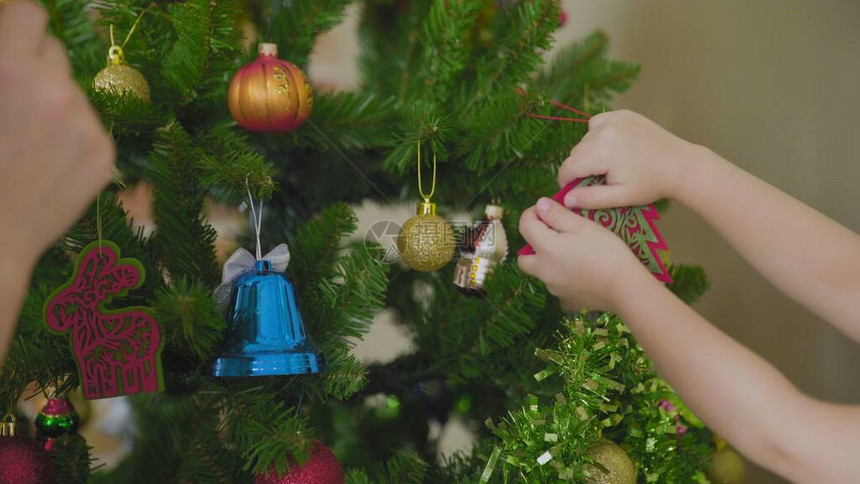 母亲和孩子在家里把圣诞树一起装饰在图片