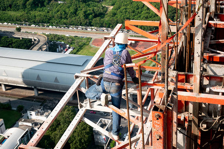 建筑工人穿戴标准个人防护设备在高层建筑工程图片
