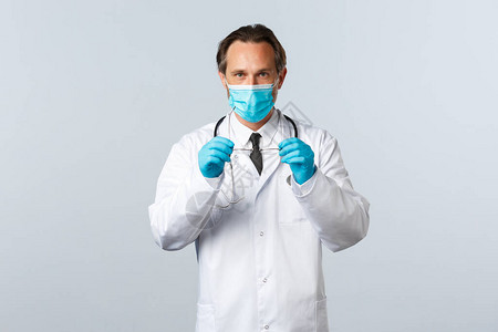 戴着医用口罩和手套戴眼镜的严肃坚定的医生图片