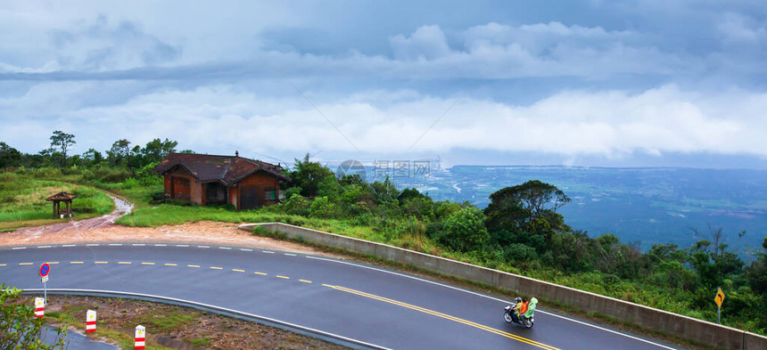高棉家庭在雨天驾驶摩托车前往山地沥青路图片