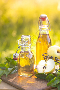 两瓶苹果醋和新鲜的成熟苹果在木质本背景图片