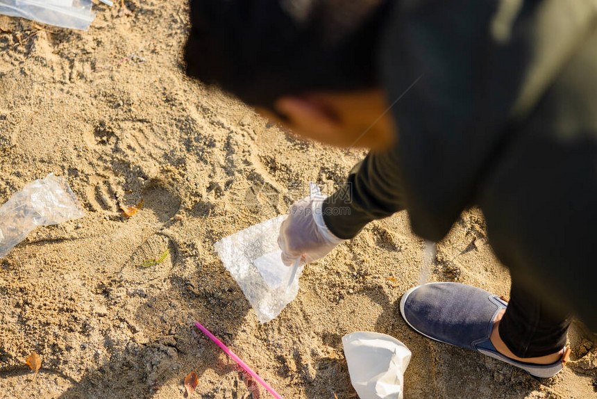 年轻人捡垃圾的顶视图志愿者正在清洁海滩他正在保护图片