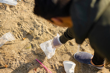 年轻人捡垃圾的顶视图志愿者正在清洁海滩他正在保护图片