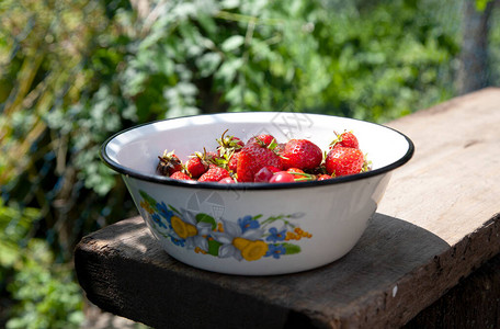 草莓和樱桃放在木桌上的老式搪瓷碗里图片