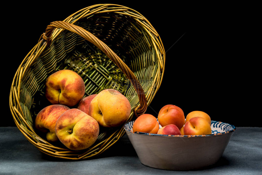陶瓷盘上的杏子和柳条篮上的桃子图片
