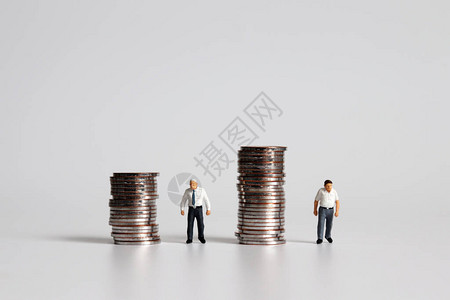 高龄津贴在不同的高度站在一堆硬币旁边的背景