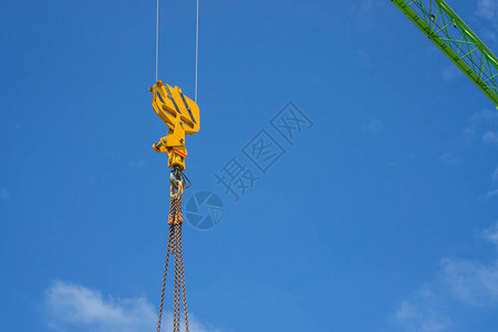 黄色钢环和链条的向上视图悬在一大型绿梁塔起重臂在明图片