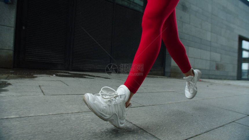 女腿在慢动作的街道上奔跑关闭了户外慢跑的女人腿穿着红色紧身裤在外面跑步的运动女人穿着运动鞋跑图片