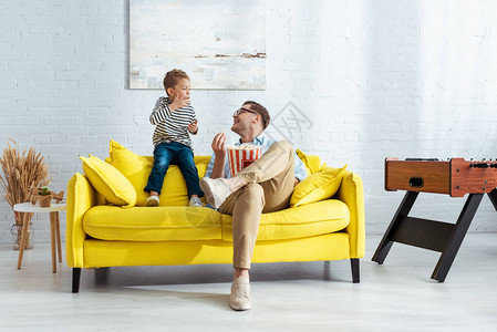 快乐的父亲和儿子坐在黄色沙图片