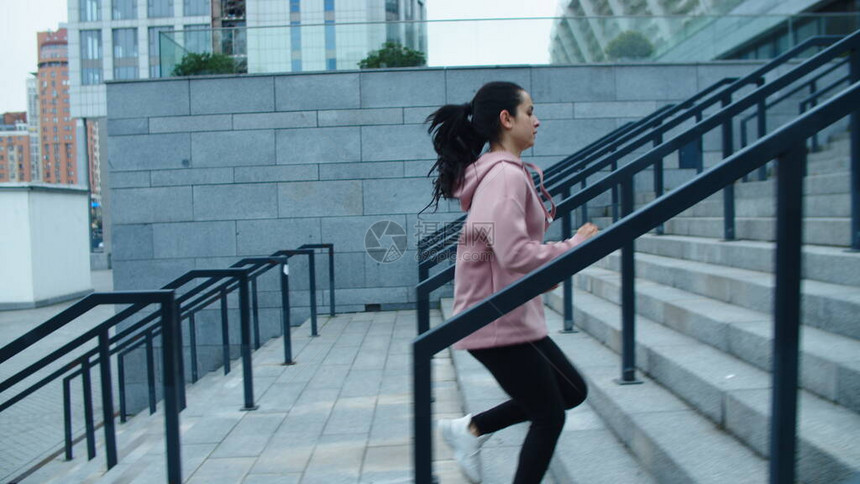 女运动员在户外锻炼上跑楼梯健身女孩慢跑在城市街道楼上的慢动作城市建筑背景下的运动女子图片