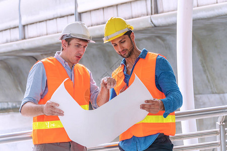 两名工程师或建筑师与安全头盔规划关于建设与蓝图图片