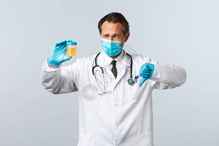医疗面具和手套中失望的医生展示尿样图片