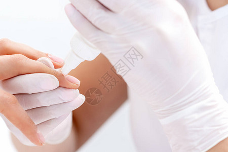 美甲专家的手正在用胶水来贴紧女人的指甲图片
