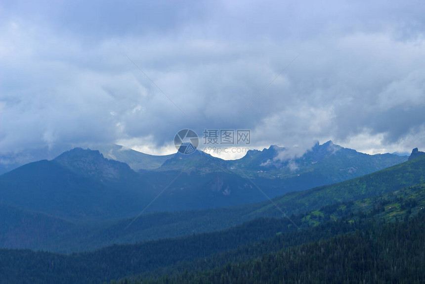 对遥远的针叶林和雾山的模糊视野阴霾中的深色西伯利亚针叶林山脉上空的低云被森林覆盖的山丘景观自然公园Ergaki图片