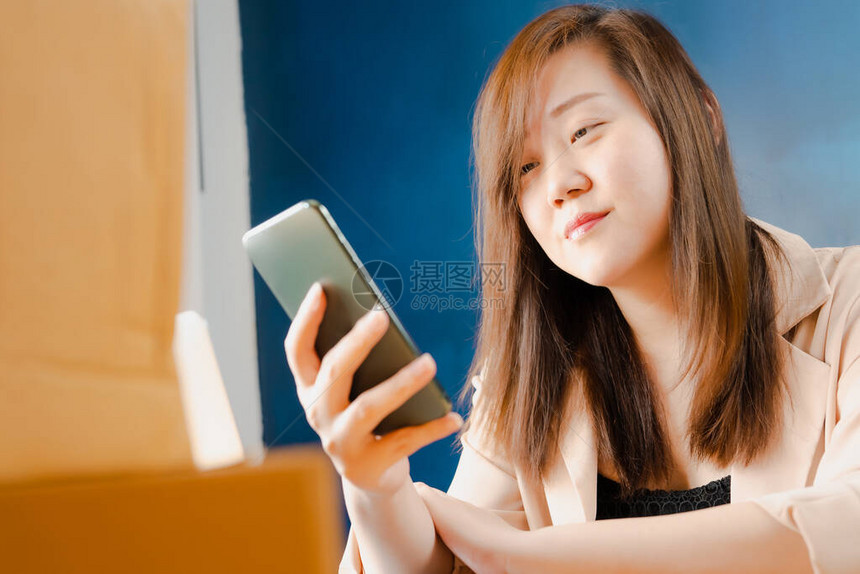 Asian商业和网上售货妇女使用电话申请来检查图片