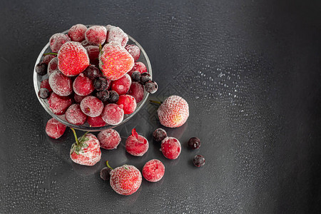 冷冻水果黑醋栗樱桃和草莓的冷冻水果混合物维生素混合物在黑暗的背景图片