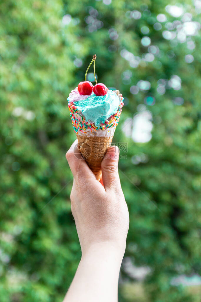 雌手握着多色冰淇淋和樱桃在淡绿色背景图片
