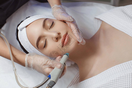 女在美容疗养院前额接受微红外膜治疗的侧面观察在美容科诊所进图片
