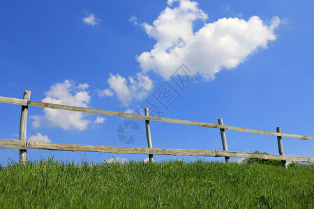 蓝天白云下绿色草地上的木栅栏图片