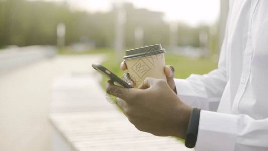 穿着白衬衫喝咖啡并使用手机4K的非裔美国人男图片