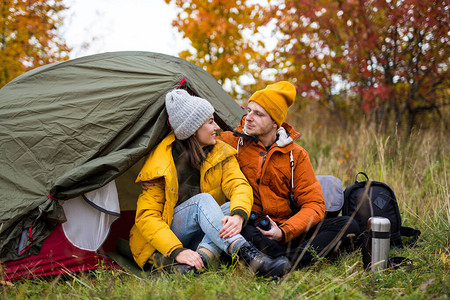 长途跋涉和徒步远足概念在秋林绿帐篷附近坐着爱情中的背景图片