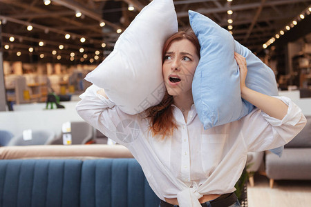 女人用枕头遮住她的耳朵在一间吵图片