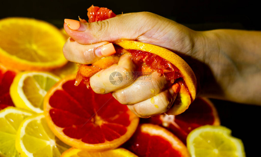 一只手挤压一片橙子的特写图片