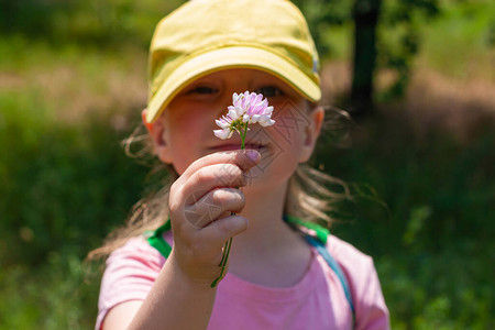 身穿黄色棒球帽粉色衬衫快乐漂亮的小女孩站在自然背景上图片