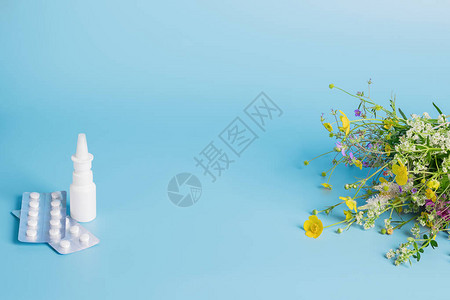 打击预防季节过敏的概念鲜花保护医用面具药丸在蓝色背景下滴药带有文本广告位置的图片