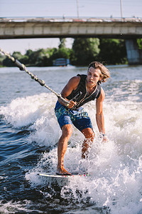 一个人正在一艘摩托艇划过的冲浪板上冲浪背景图片