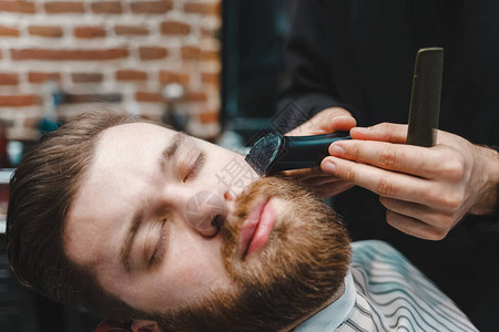 美发大师用电动修剪器为客户剪胡须图片
