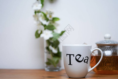 一杯茉莉花茶壶和背景中的白色茉莉花图片